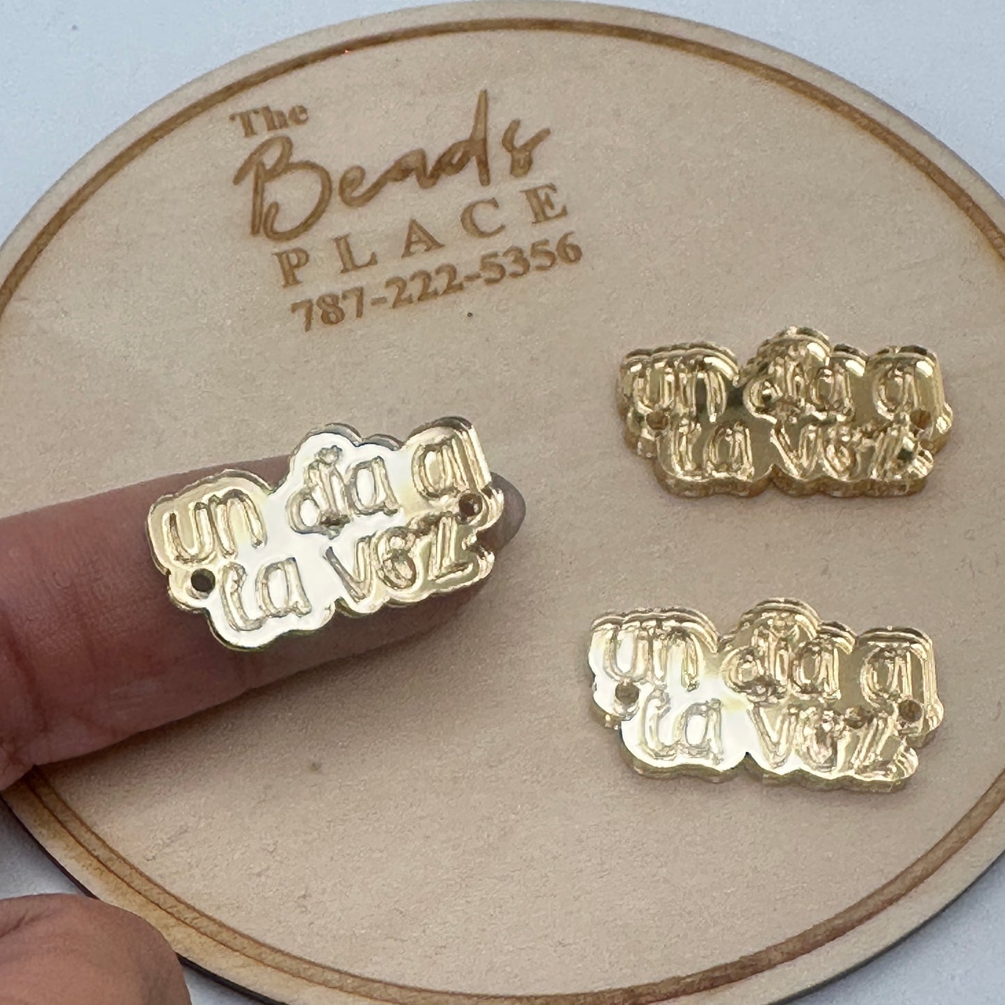 Conector con frase “Un día a la vez” en acrílico dorado